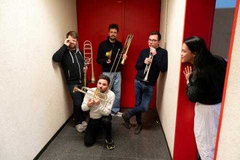 5 darstellende, 4 mit Blasinstumenten, einer schaut an der seite aus einer Tür