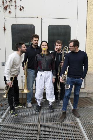 5 Darstellende, 4 mit Blasinstumenten, einer in der Mitte mit Entenschnabel