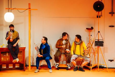 Vier Musiker sitzen vor einer Wand und unterhalten sich